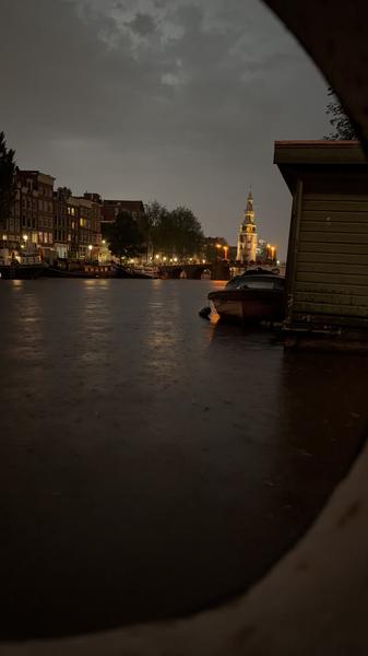 A serene evening scene by a canal or river with a boat and buildings in the background